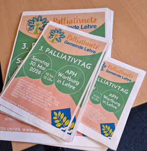 Bild vergr&ouml;&szlig;ern: Plakate zum Palliativtag in mehreren Größen líegen gestapelt auf einem Tisch.