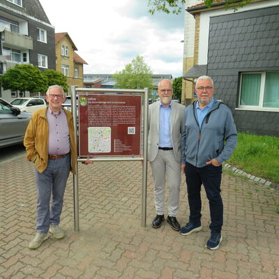 Ortsheimatpfleger Wilhelm Knigge, Verwaltungsleitung Tobias Breske und Ortsbürgermeister Heinrich Köther mit der neuen Infotafel auf dem Marktplatz.
