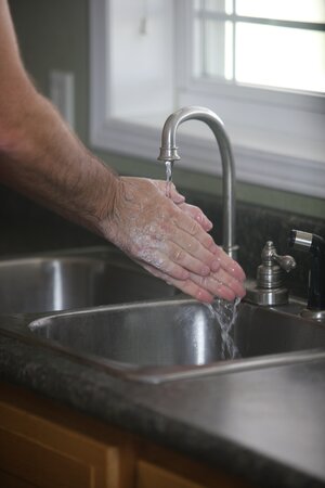 Bild vergr&ouml;&szlig;ern: Eine männliche Person wäscht sich die Hände unter einem Wasserhahn.