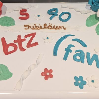 Eine rechteckige Torte mit Blumenverzierungen und der Aufschrift 5 BTZ und 40 FAW.