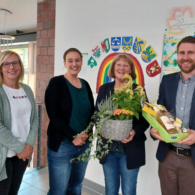 Auf dem Bild stehe Vanessa Rothermund, Julia Carluccio , Kerstin Bock und Julian Sprenger nebeneinander. Kerstin Bock hält eine bepflanze Blumenschlae in den Händen und Julian Sprenger ein Präsent.